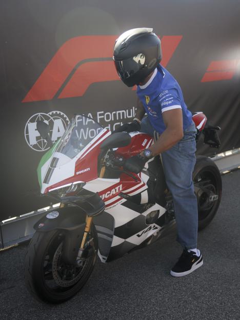 Lewis Hamilton riding a red motorbike through a crowd of fans.
