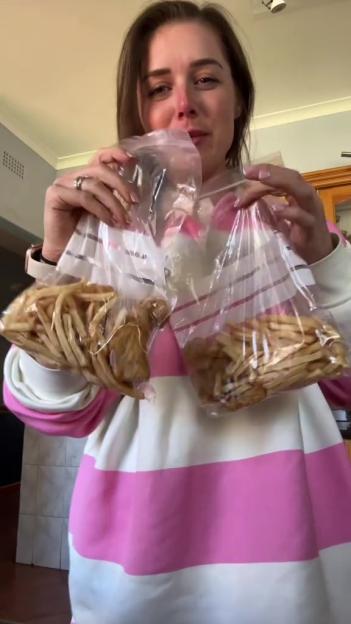 Woman holding two bags of french fries.