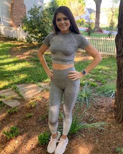Woman in gray athletic wear standing outdoors.