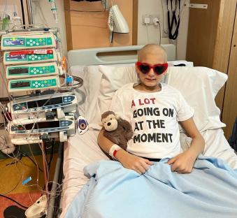 A 12-year-old girl in a hospital bed wearing heart-shaped sunglasses.