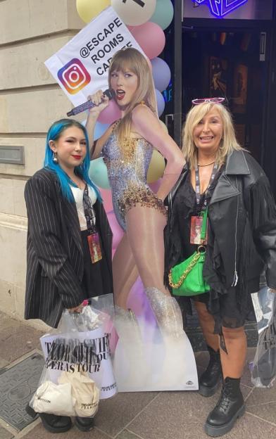 Two women pose with a Taylor Swift cutout at a Taylor Swift Eras Tour event.
