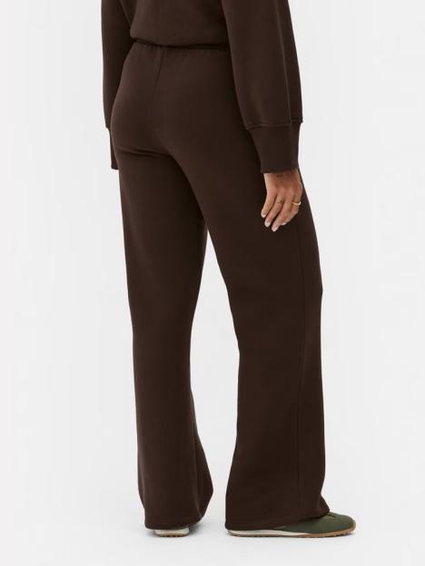 Back view of a person wearing brown joggers and sneakers.