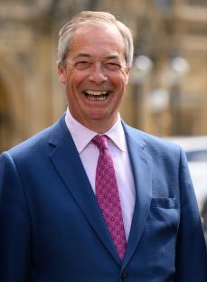 Nigel Farage smiling outside Parliament.