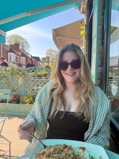 Lydia Pettet smiling while eating outside at a restaurant.
