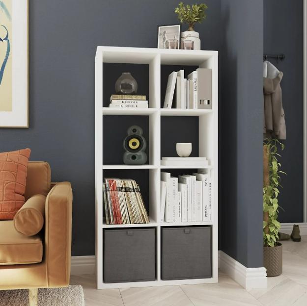 White cube shelf with books, speaker, and storage boxes.