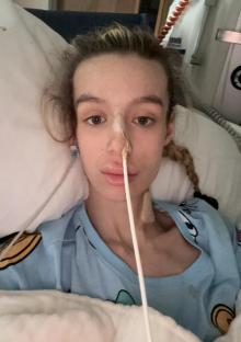 A young woman in a hospital bed with a nasal cannula.