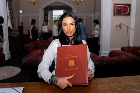 Katie Price holding the Cambridge Union Society visitor's book.
