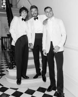 Black and white photo of David Beckham with his two sons in white dinner jackets.