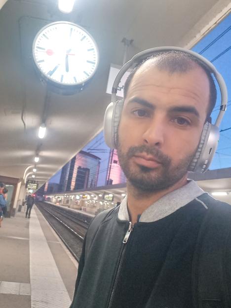 A man wearing headphones takes a selfie at a train station in Brussels.