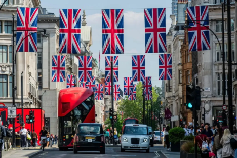 Street scene in London with Union Jack flags hanging overhead.