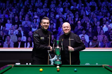 Mark Selby and John Higgins holding a trophy after a snooker match.