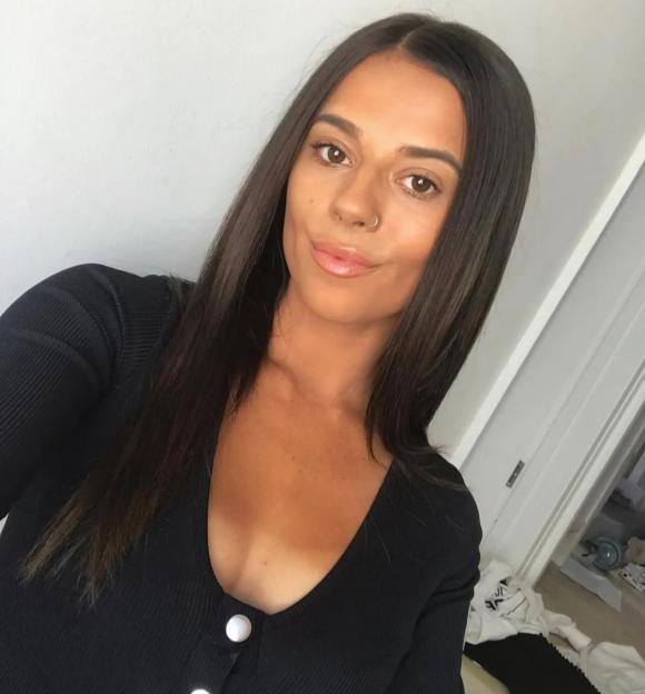 Selfie of a young woman with long brown hair and a nose ring.
