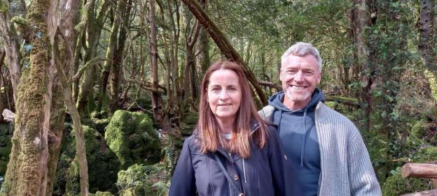 Portrait of a man and woman standing in a forest.