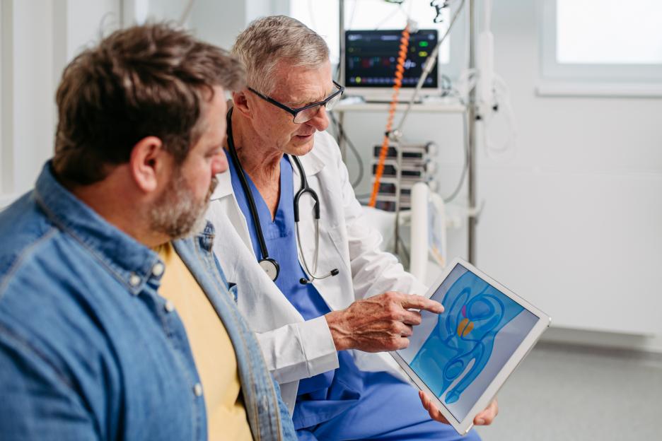 Doctor explaining prostate examination to a patient using a tablet.