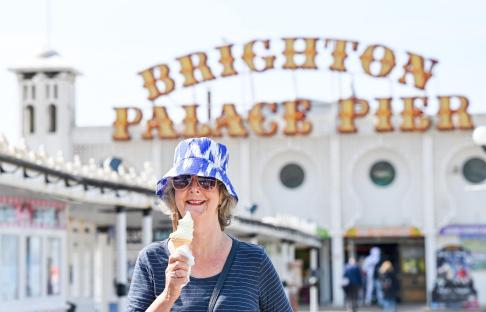 Woman eating ice cream in front of Brighton Palace Pier.