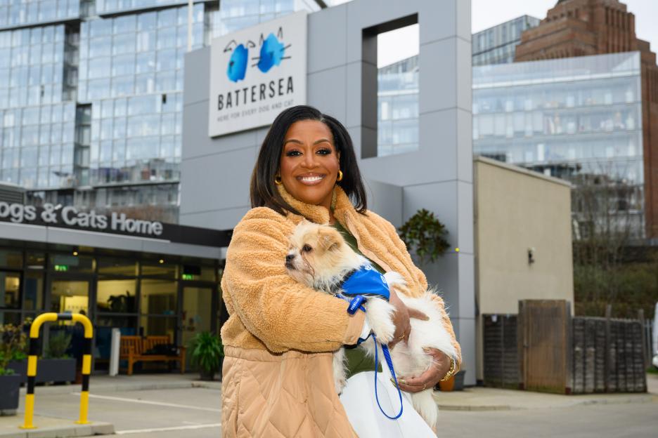 Alison Hammond holding a small dog outside Battersea Dogs & Cats Home.