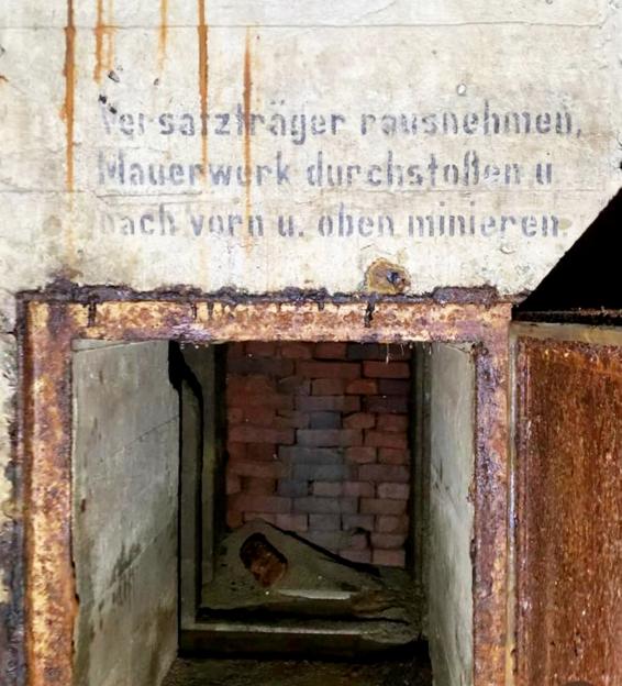 Interior of a World War II German bunker with German writing on the wall.