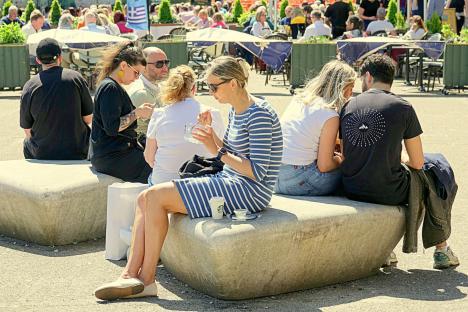 People sitting on stone benches in a sunny city center.
