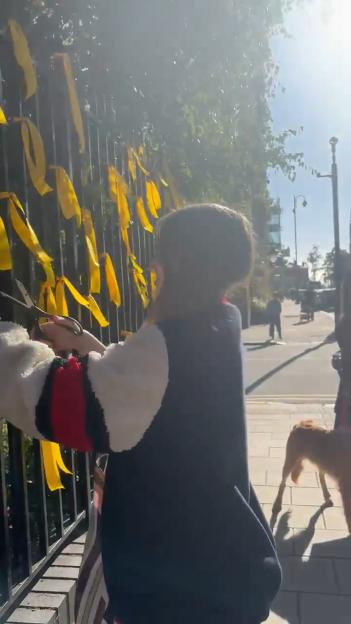 Nadia Yahlom cutting down yellow ribbons for Israeli hostages on a memorial.