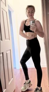 Woman in workout clothes taking a selfie in a mirror.