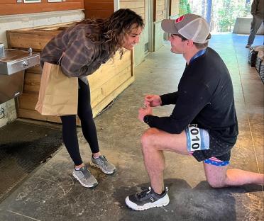 A man kneeling to propose to a woman.