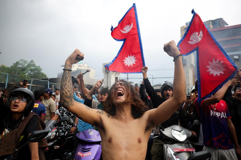 Demonstrators celebrate at the Parliament complex with Nepali flags during a protest.