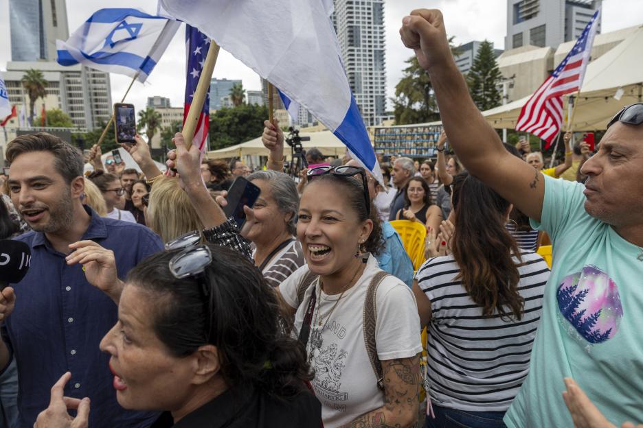 People celebrating in Tel Aviv with Israeli and American flags.