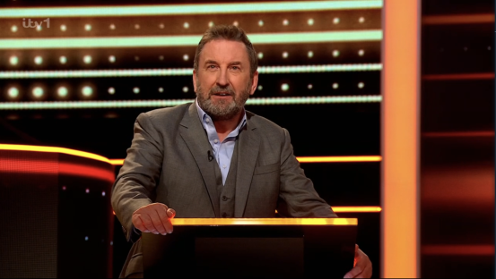 Screenshot of a man in a suit hosting a game show.