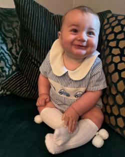Smiling baby in blue romper and white socks.