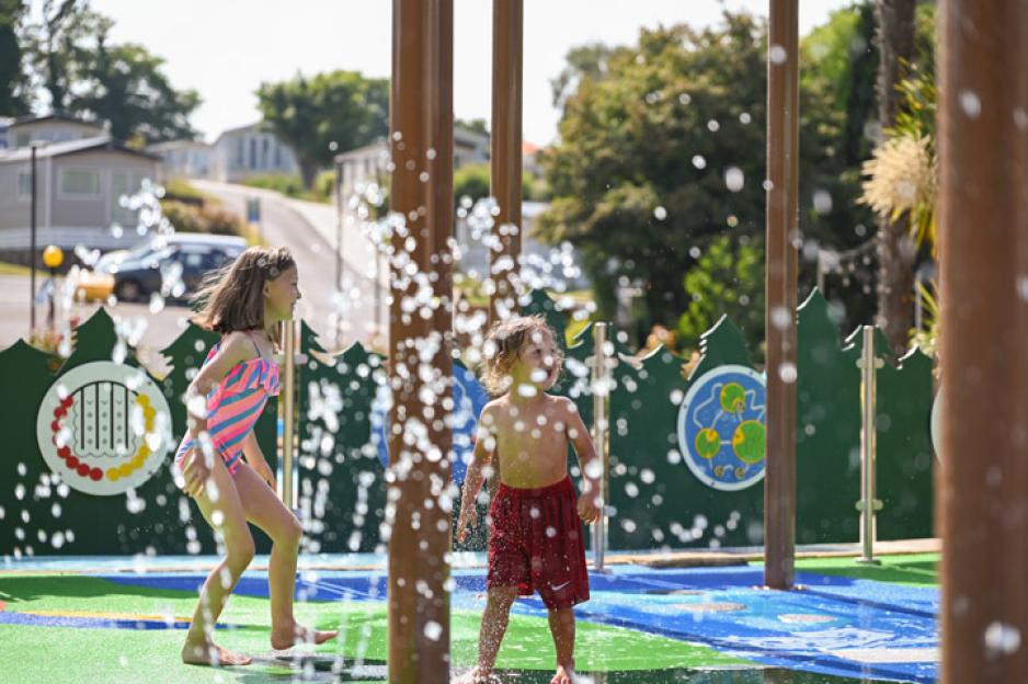 Two children playing in a water spray park.