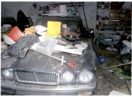 A cluttered car hood with various items on top, including tools and debris.