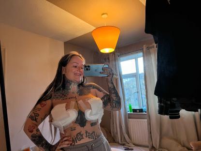 Woman with tattoos taking a selfie after breast reduction surgery.