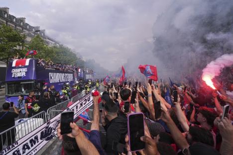 PSG players on a celebratory parade bus, cheered by fans.