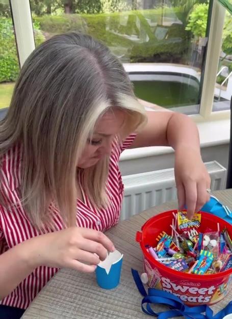 Person filling small blue cups with candy to make party favors.