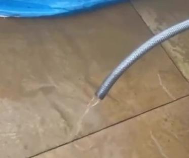 Siphoning water from a paddling pool using a hose.