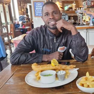 Man sitting at a pub table eating fish and chips.