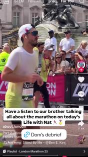 A man in a white shirt finishes a marathon, being helped by another runner.