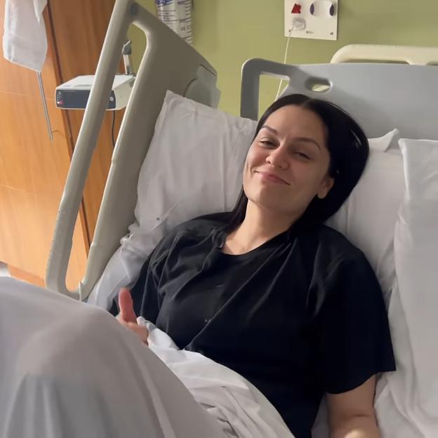 Jessie J in a hospital bed giving a thumbs up.