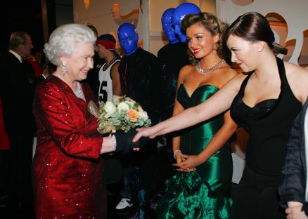 a woman in a green dress shakes hands with queen elizabeth