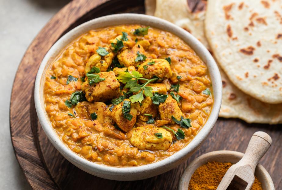 Bowl of lentil dahl with chicken and naan bread.