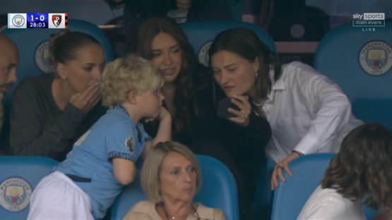 Screenshot of people whispering in a stadium.