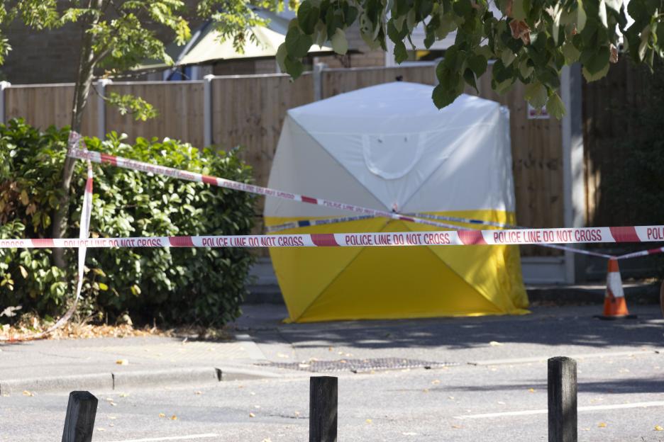 Crime scene with police tape and forensic tent.