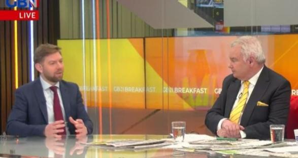 Two men in suits sitting at a table discussing reform on a news program.