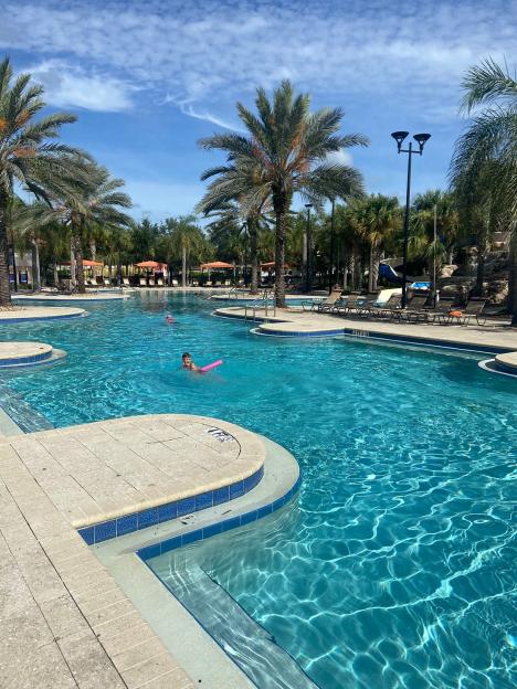 Solterra Resort pool with palm trees and a child swimming.