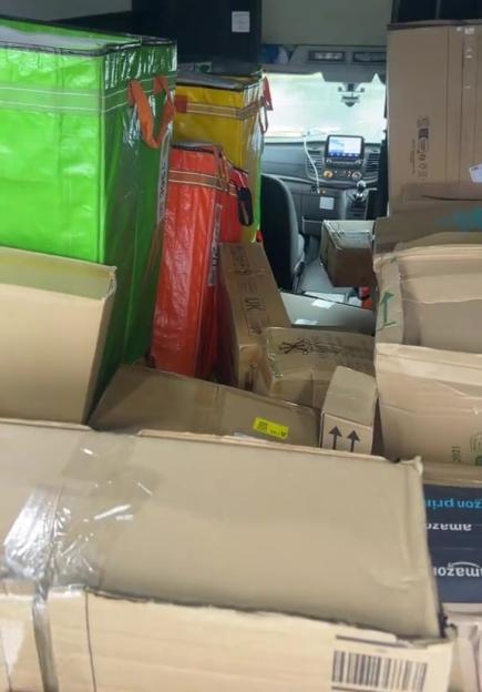 The back of a delivery van, completely full of boxes and brightly colored delivery bags.