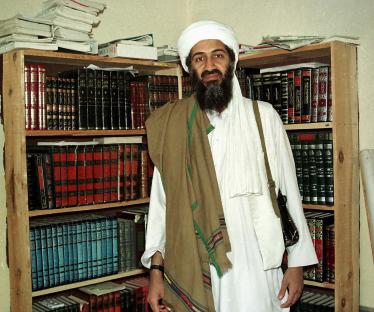 Osama bin Laden standing in front of bookshelves.