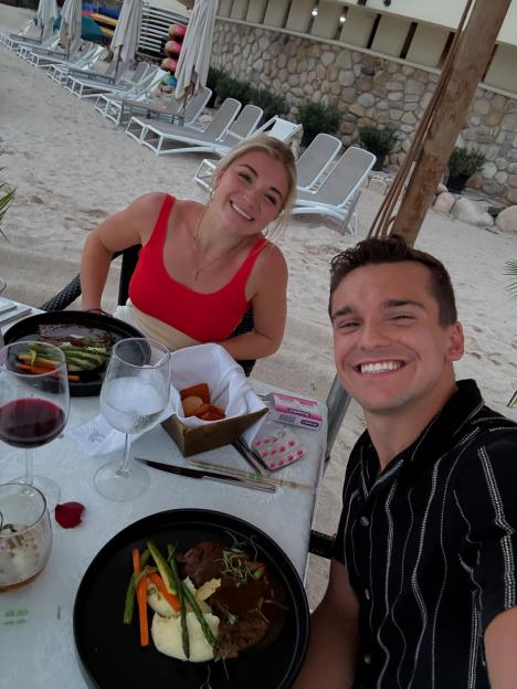 Abby and Matt Howard smiling while having dinner on the beach.