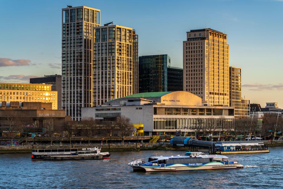 A Thames Clipper river bus on the Thames, passing the Royal Festival Hall in London.