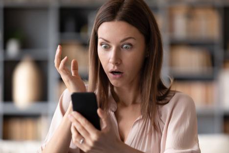Shocked young woman looking at her phone.