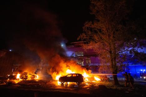 Firefighters extinguishing burning cars at the site of a drone strike in Kyiv.